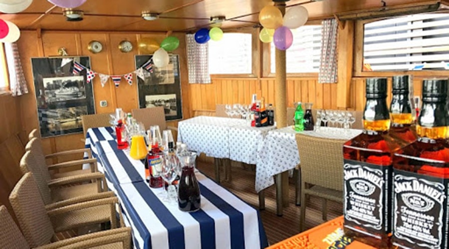 dolny pokład statku na wynajem ze stołami zastawionymi jedzeniem i alkoholem czeka na wynajem partyboat