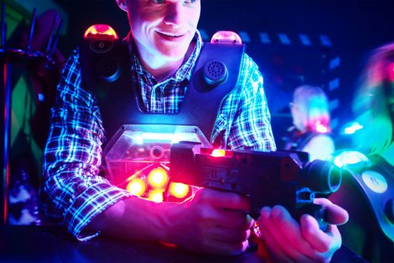 uśmiechnięty facet z bronią laserową szykuje się do paintballa laserowego w warszawie na kawalerskim